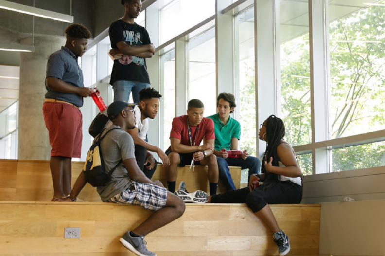 Students sitting on the wooden steps inside the Clough Undergraduate Learning Commons