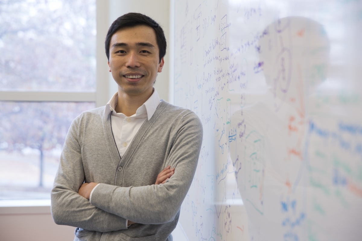 CSE Associate Professor Polo Chau stands in front of a white board with equations written on it.